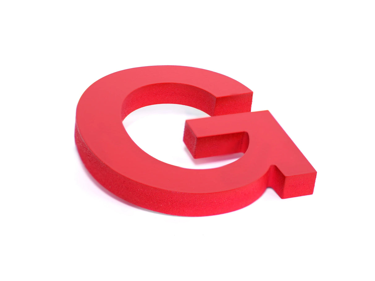 Red PVC plastic letter G on it's side with a smooth face and rough sides.