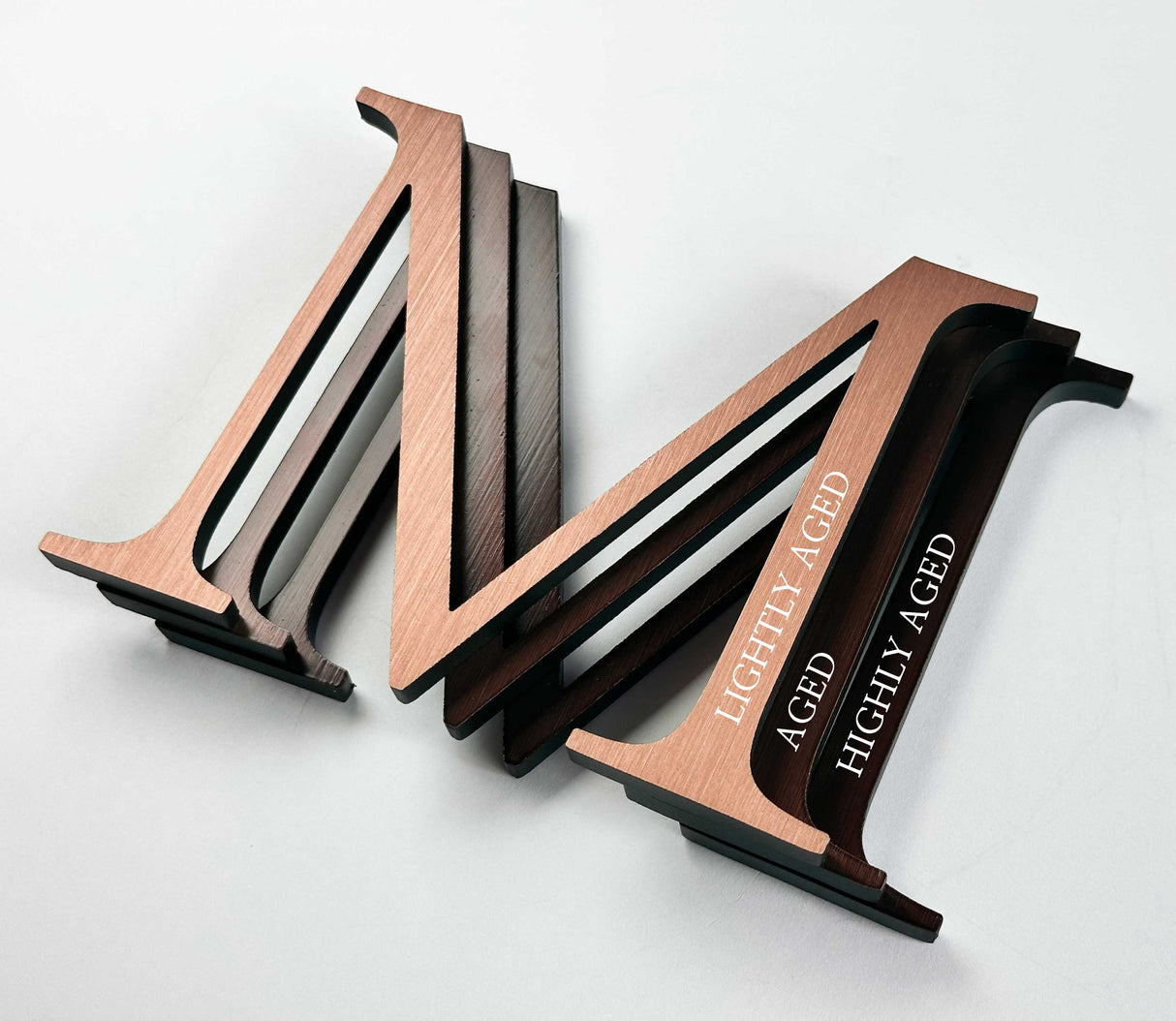 Comparison of solid copper division 10 architectural sign letters with light, medium, and high levels of aging