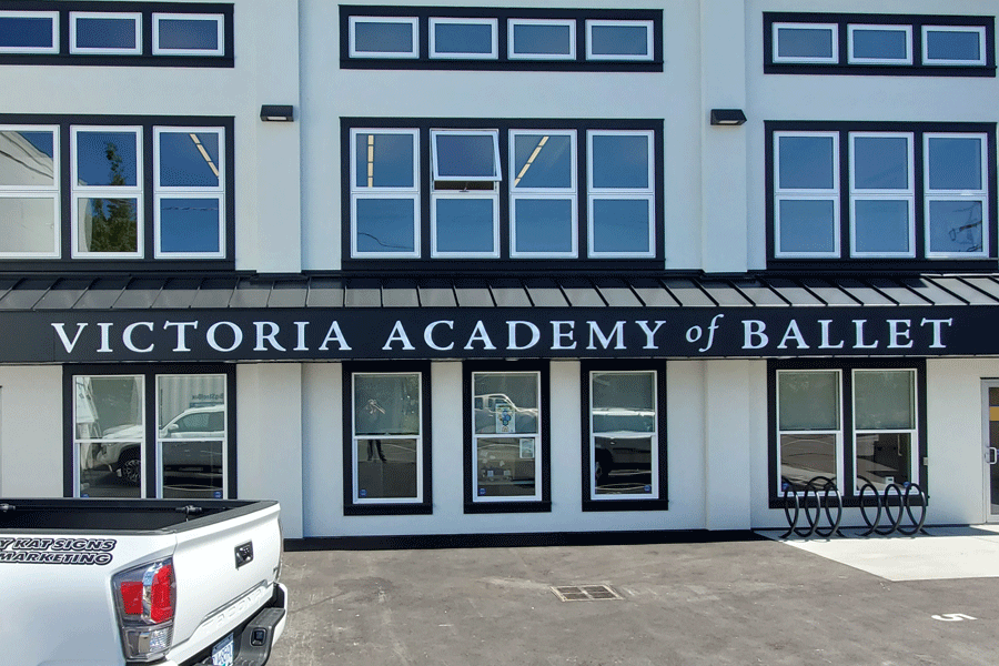 Exterior dance studio sign with unpainted white acrylic sign letters.