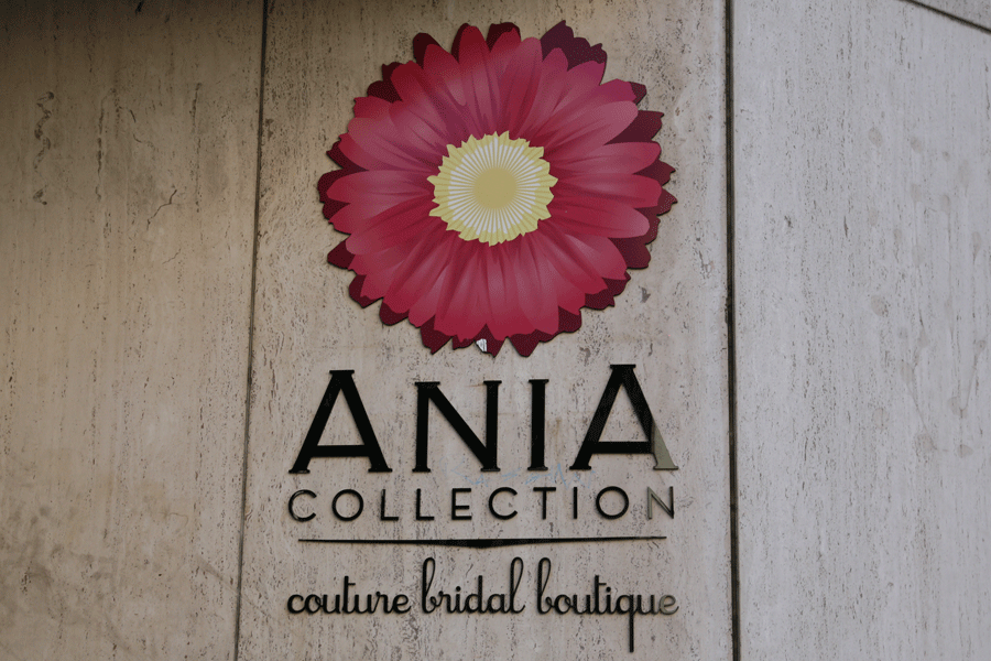 A bridal boutique's storefront sign black flat cut acrylic sign letters and a multi-layered pink flower logo.