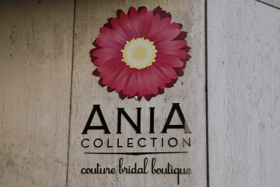 A bridal boutique's storefront sign black flat cut acrylic sign letters and a multi-layered pink flower logo.