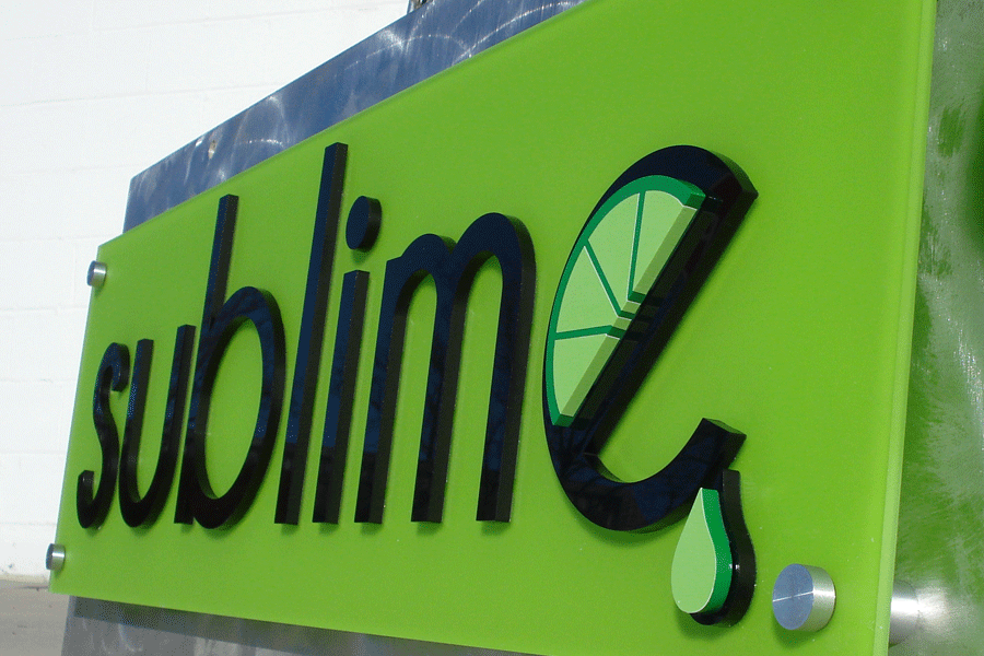 A green flat cut acrylic storefront sign displaying a logo with  black sign letters and a lime wedge.
