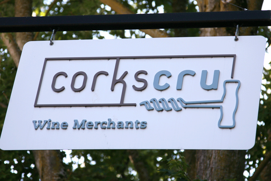 A projecting flat cut acrylic store sign for Corkscru Wine Merchants with painted sign letters and a corkscrew logo.