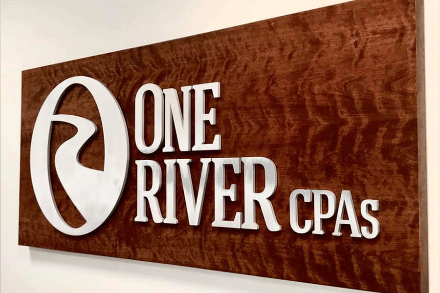 Business sign with stainless steel sign letters on a wooden plaque.