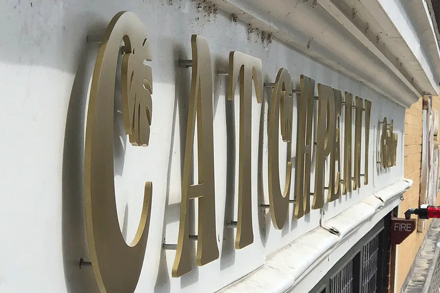 Storefront sign with aged brass sign letters and shapes.