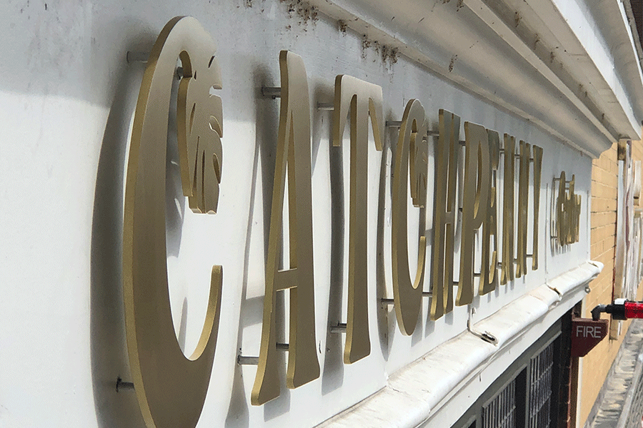 Storefront sign with aged brass sign letters and shapes.