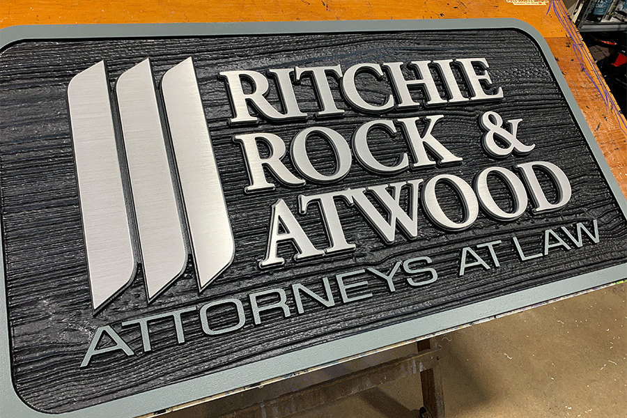 Law office sign with brushed aluminum sign letters on a black plaque.