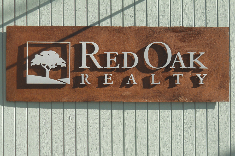 An exterior business sign with aluminum or stainless steel sign letters on a weathered steel background.
