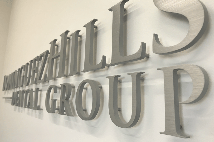 A dental office sign with brushed aluminum sign letters.