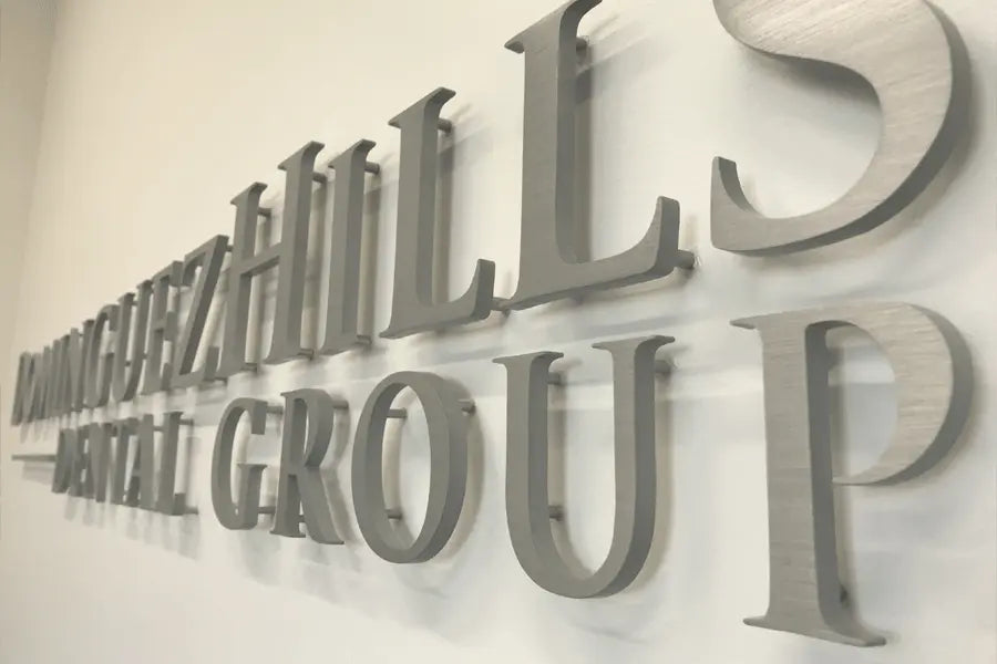 A dental office sign with brushed aluminum sign letters.