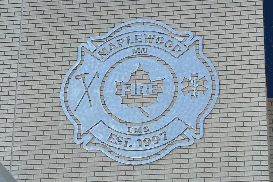 An exterior aluminum wall sign with a radial arc brushed finish.