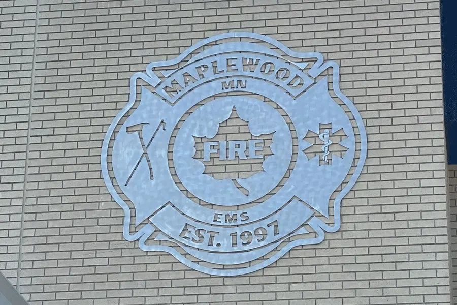 An exterior aluminum wall sign with a radial arc brushed finish.