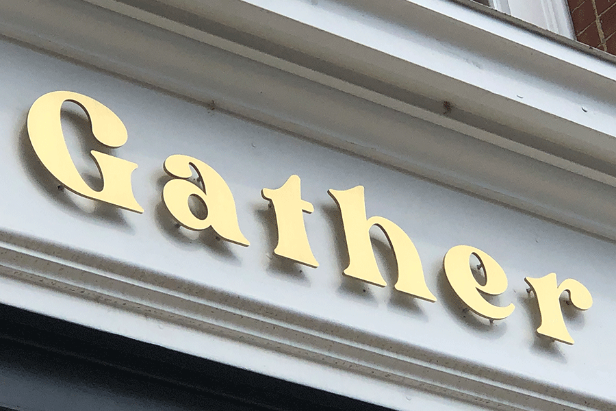 Exterior storefront sign with polished brass sign letters.