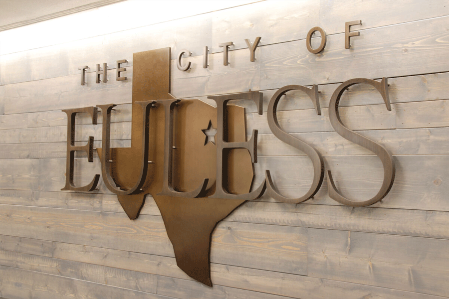 Municipal city sign with aged bronze sign letters and an aged bronze cutout of the state of Texas.