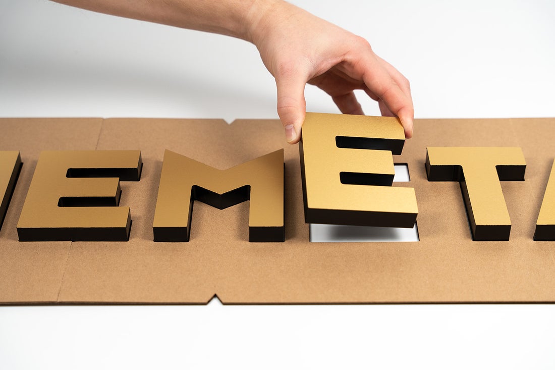 A rigid stencil sign mounting guide with a hand lifting one letter out of the guide.