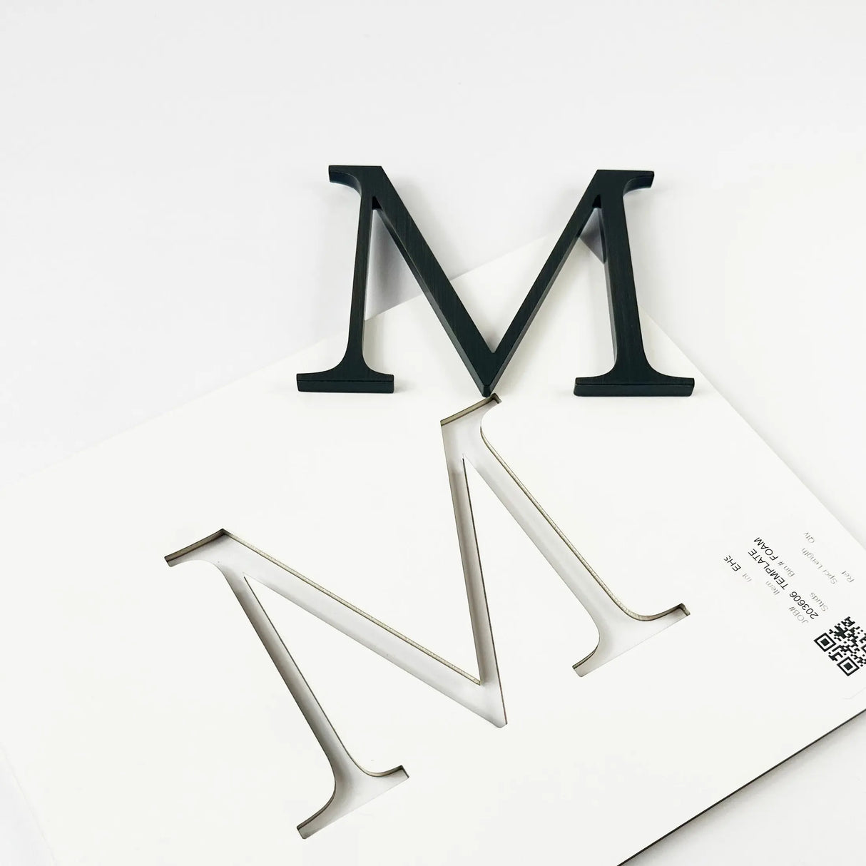 Heavily aged brass division 10 architectural sign letter with double-sided tape on mounting template