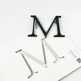 Heavily aged brass division 10 architectural sign letter with double-sided tape on mounting template
