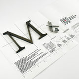 Heavily aged solid brass division 10 architectural sign letter on mounting template with hardware