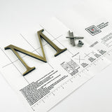 Lightly aged solid brass division 10 architectural sign letter on mounting template with hardware