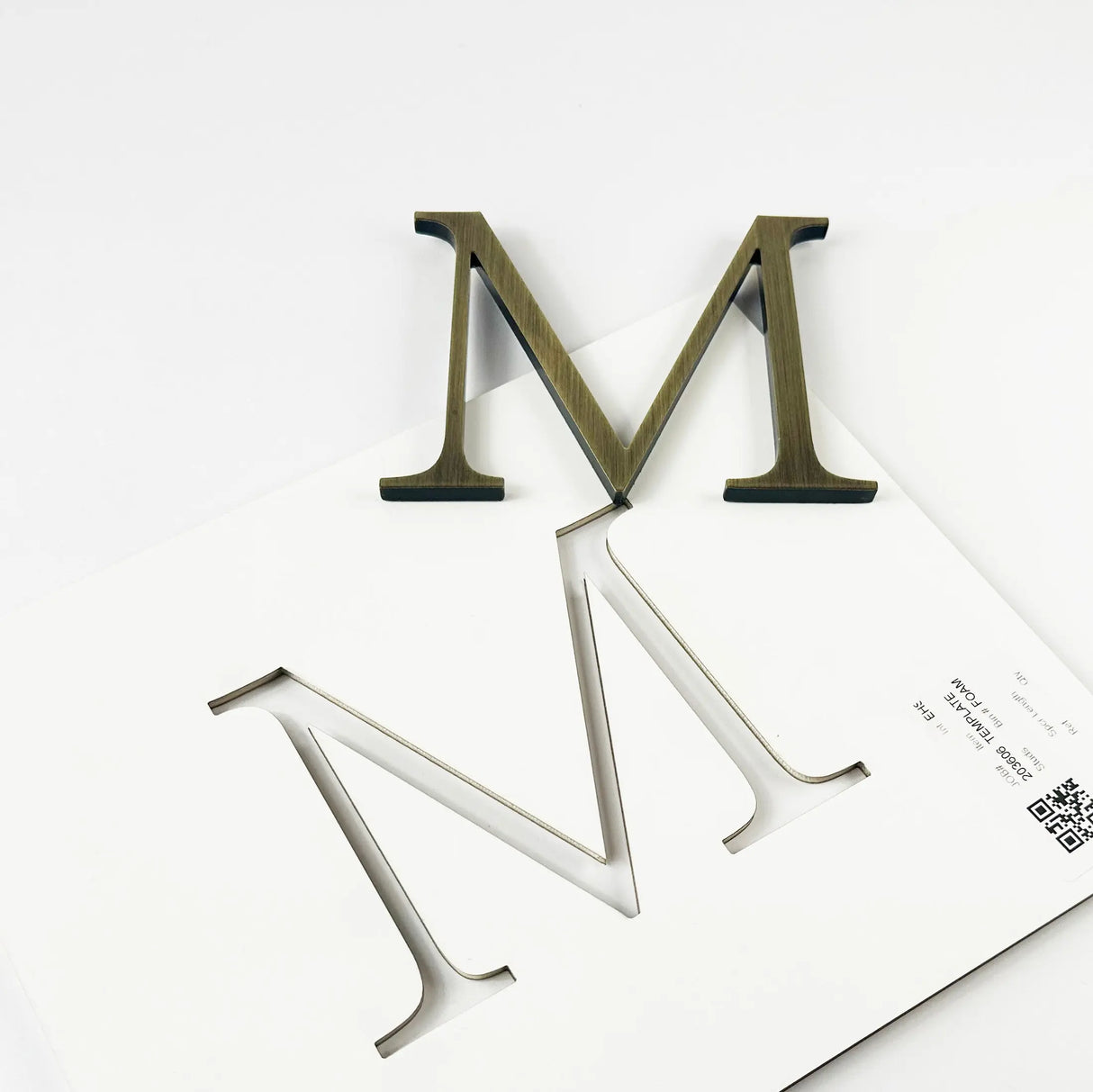 Medium aged brass division 10 architectural sign letter with double-sided tape on mounting template