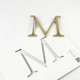 Light aged brass division 10 architectural sign letter with double-sided tape on mounting template