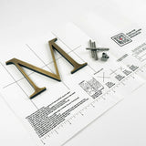 Lightly aged solid bronze division 10 architectural sign letter on mounting template with hardware