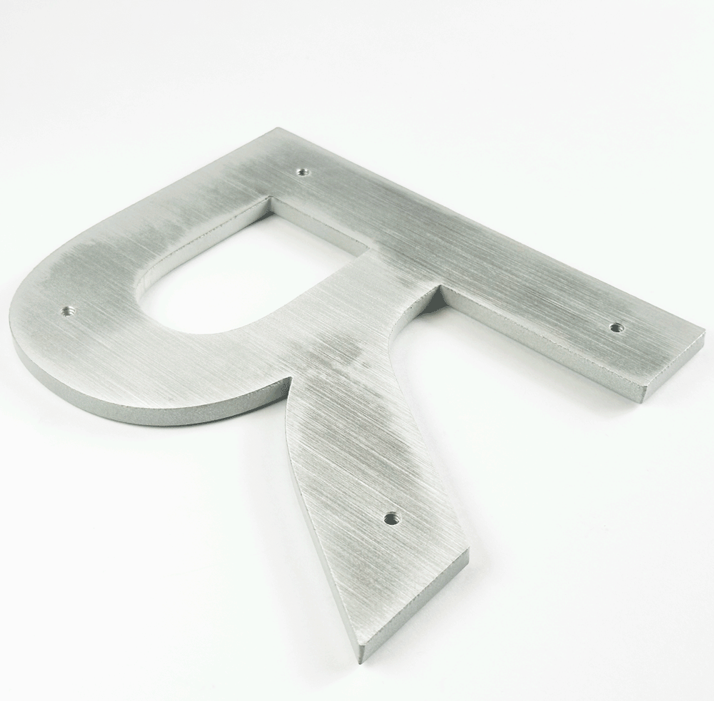 Solid aluminum sign letter animating installation of back studs and spacers